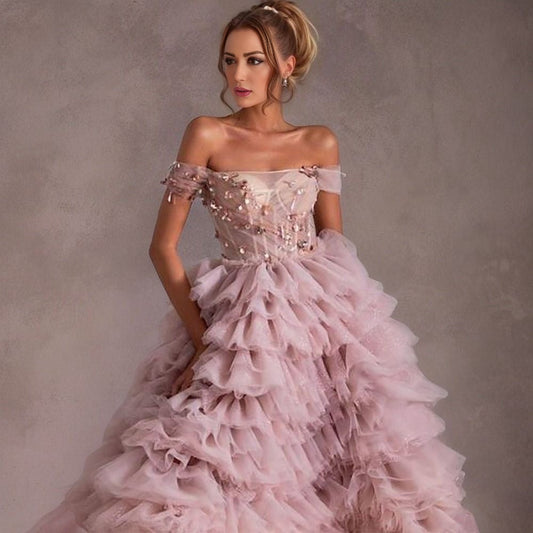 Off-the-Shoulder Pink Gown: The model poses to highlight the off-the-shoulder design, with delicate gems and sequins catching the light.