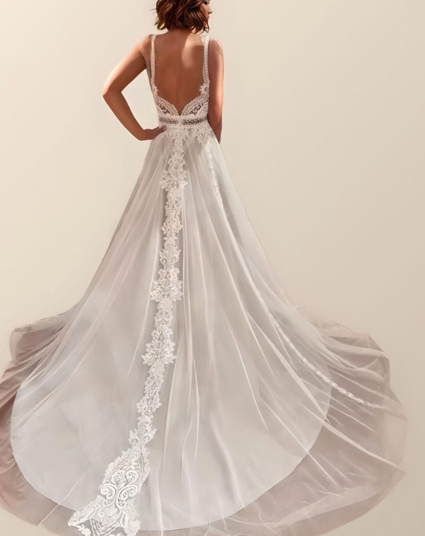 Backless Lace Bridal Gown: The bride poses from behind, emphasizing the backless design and delicate spaghetti straps of the gown.