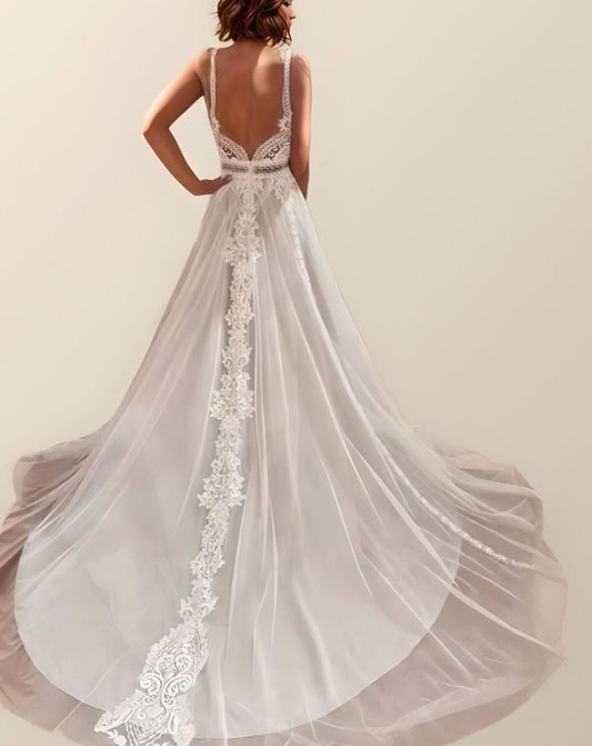 Backless Lace Bridal Gown: The bride poses from behind, emphasizing the backless design and delicate spaghetti straps of the gown.