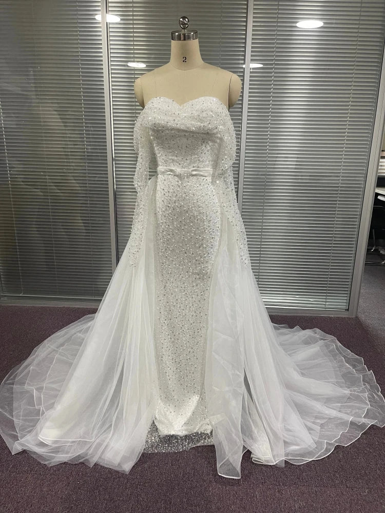 Tailor manequin in a sequined off-the-shoulder mermaid gown with a detachable overskirt, perfect for a dramatic wedding look.