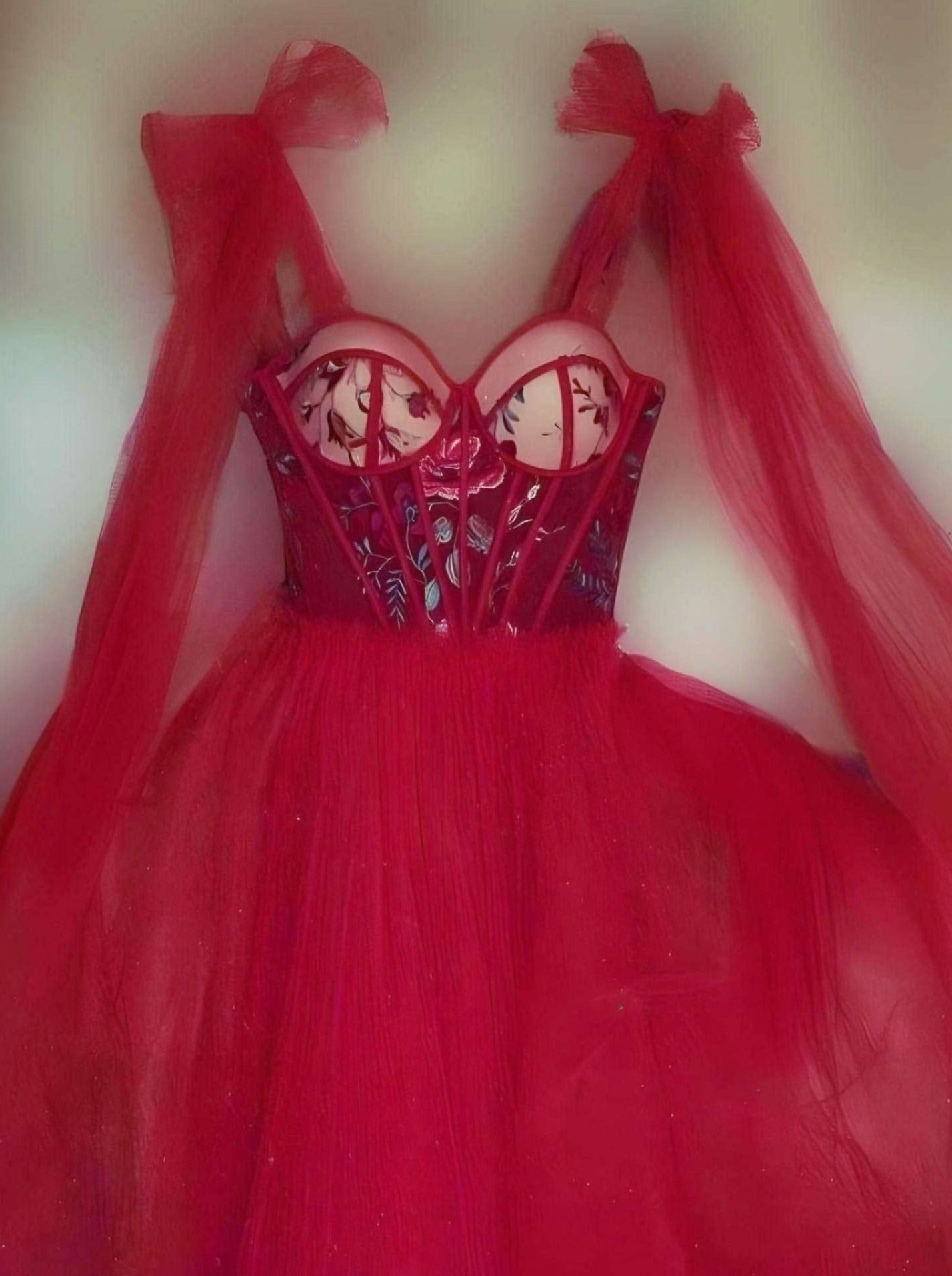 Stunning red prom dress with floral appliques on the bust, bow straps, and a flowing tulle A-line skirt.