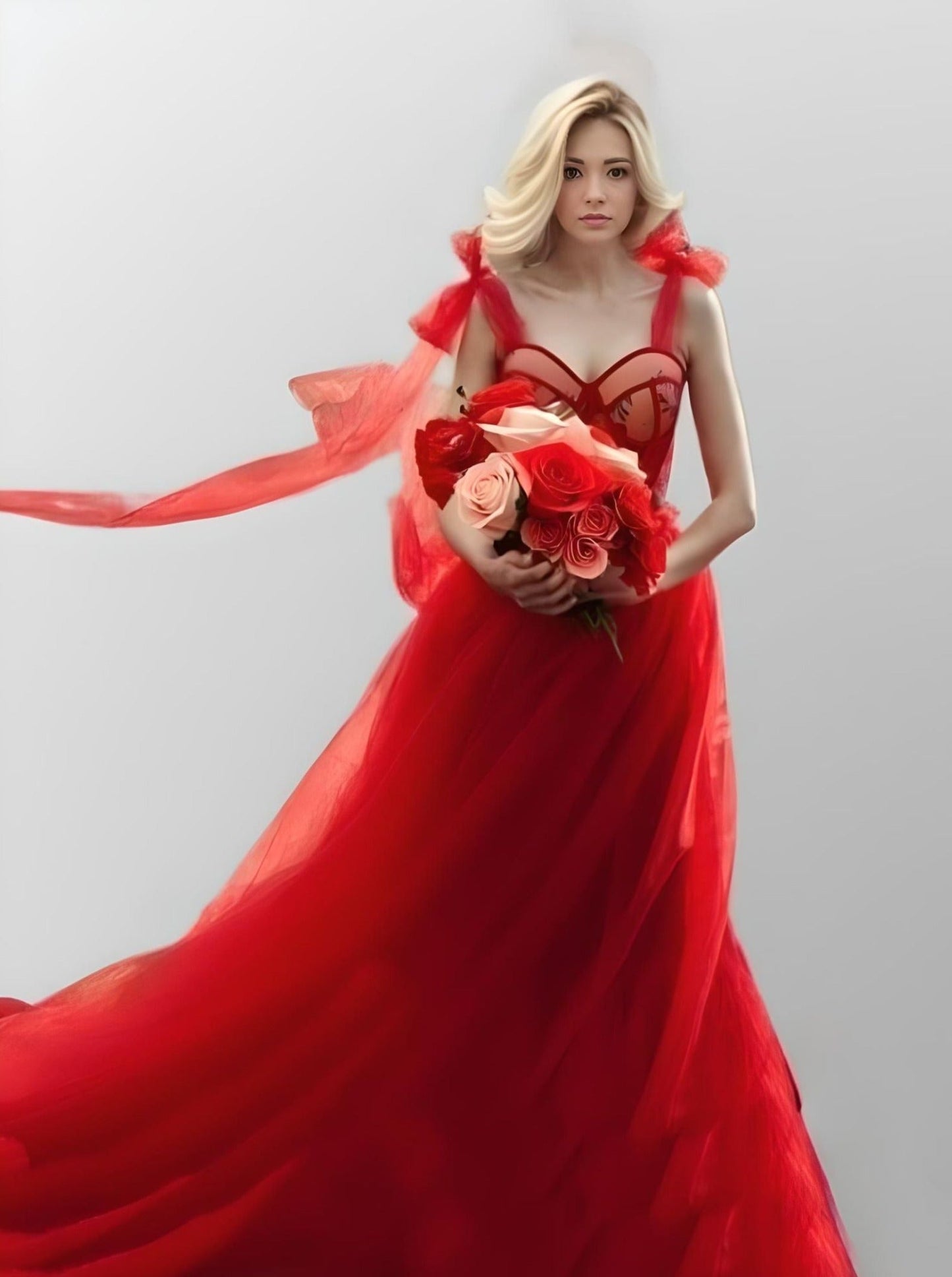 Model in a vibrant red tulle gown with sweetheart neckline, bow straps, and floral appliques on the bust.
