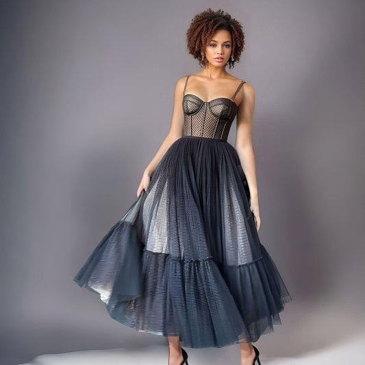 Model showcasing a black dotted tulle prom dress with a corset-style top and sweetheart neckline.