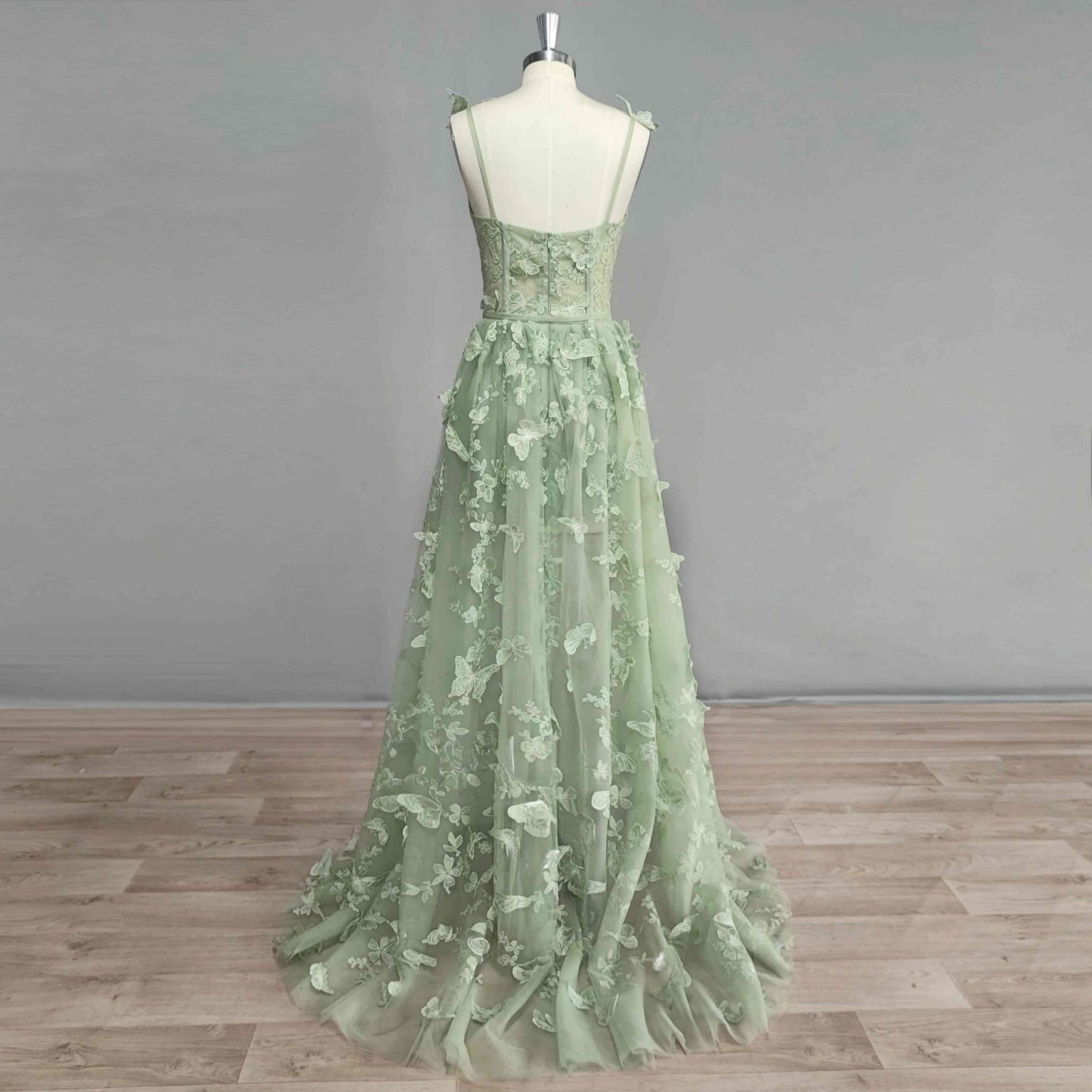 Model showcasing back of a floor-length dress with 3D butterfly appliques and boning support.