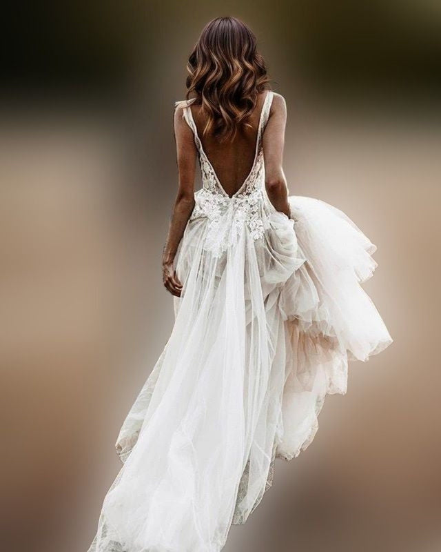 Bride in stunning backless wedding gown with lace appliques and a transparent tulle skirt, creating a sexy boho-chic look.