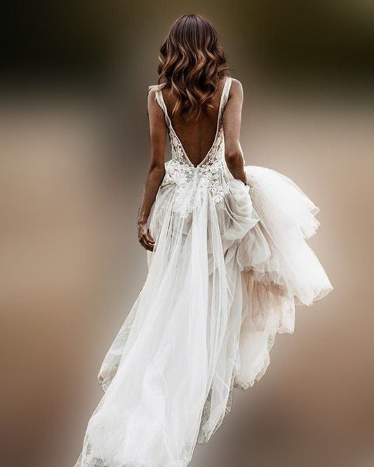 Bride in stunning backless wedding gown with lace appliques and a transparent tulle skirt, creating a sexy boho-chic look.