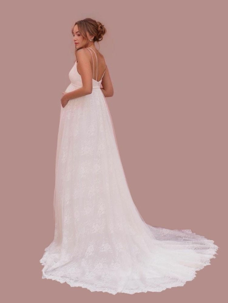 Beautiful pregnant bride in a backless wedding dress with a lace skirt and sweep train, showcasing andouble spaghetti straps on back.