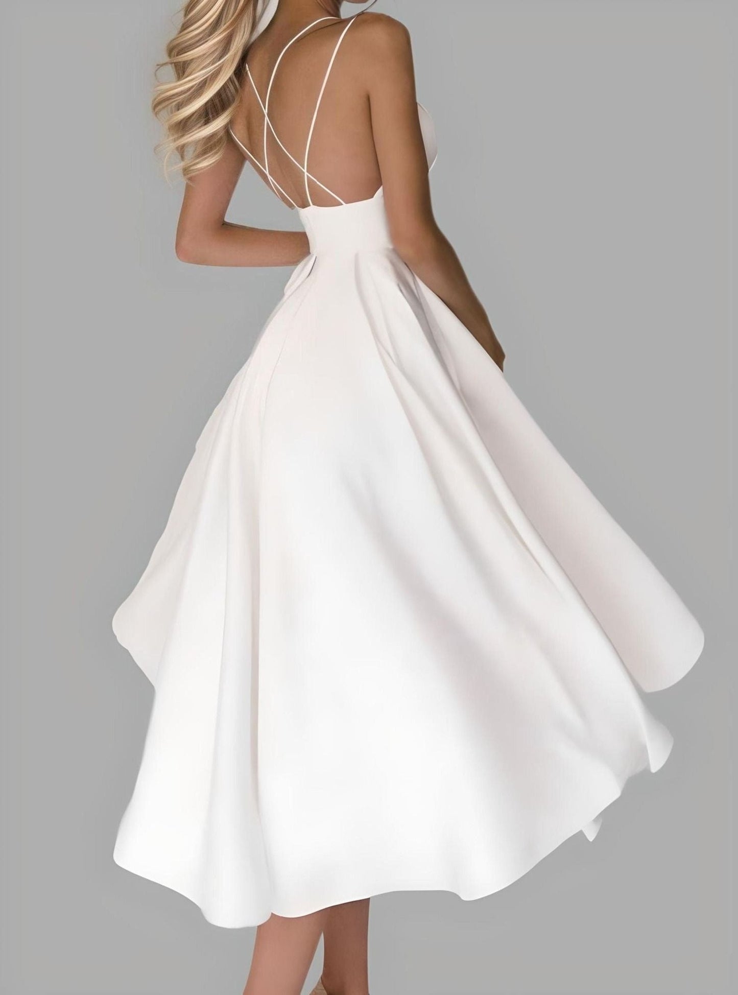 Model in sophisticated short wedding dress with a defined waist and backless criss-cross design, featuring a tea-length pleated skirt.