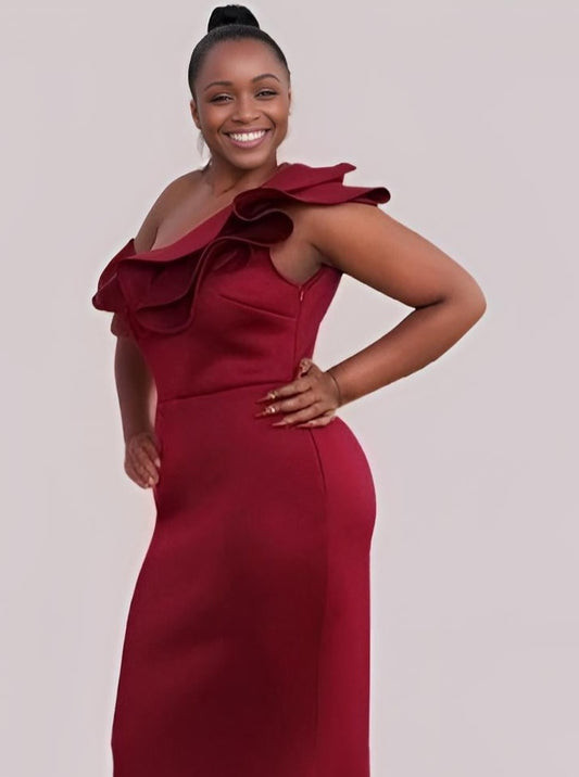 Curvy woman in burgundy formal dress with ruffled one-shoulder design.