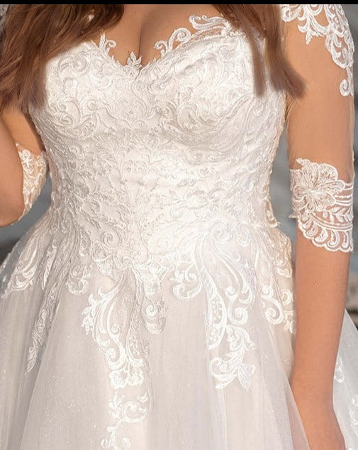 Elegant plus-size wedding dress featuring a V-neck, lace appliques on top part, and a flattering A-line skirt with lace.