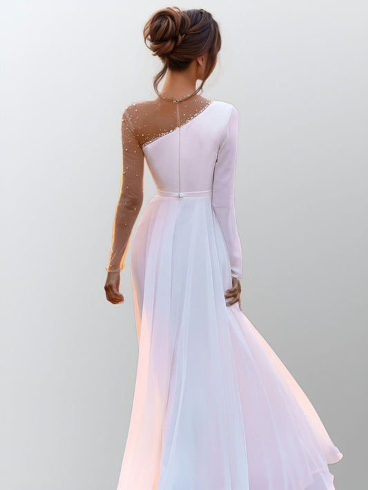 Woman in elegant wedding gown featuring a one-shoulder neckline and long sleeve in skin-colored tulle with beaded detailing.