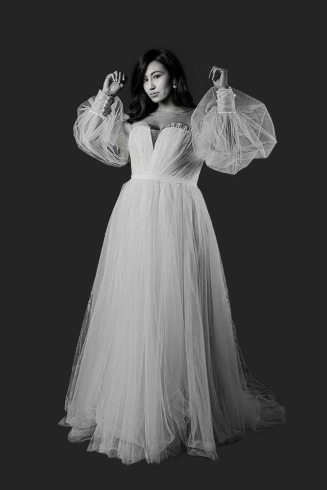 Bride showcasing a tulle A-line wedding dress with puff sleeves and a sweep train, perfect for a light and airy beach or boho wedding style.