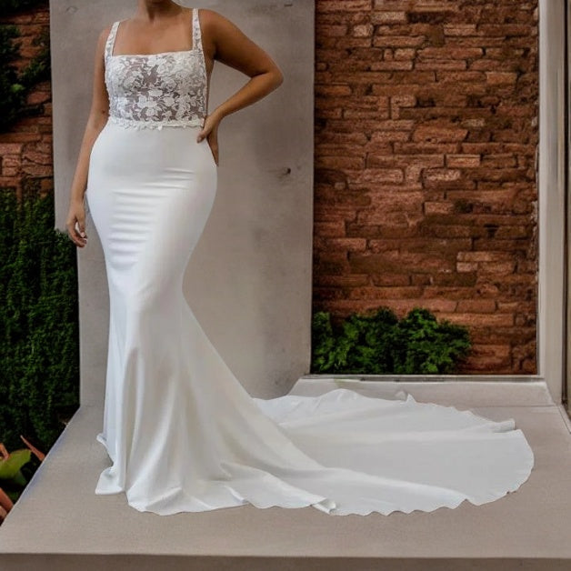 Curvy bride in a satin wedding dress with a square neckline, lace details, and a flowing sweep train.