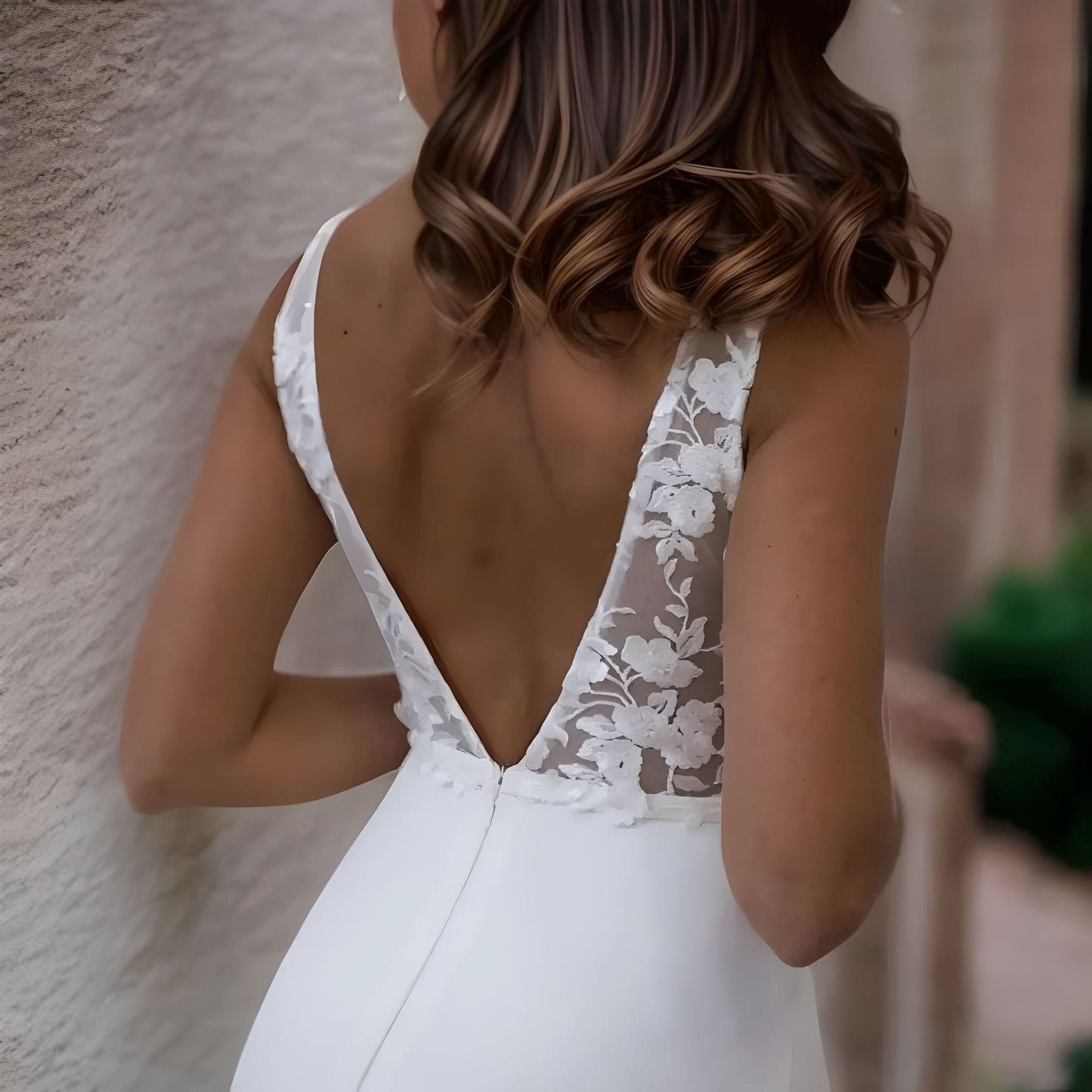 Model showcasing a boho-chic mermaid wedding gown with lace appliques and backless design.