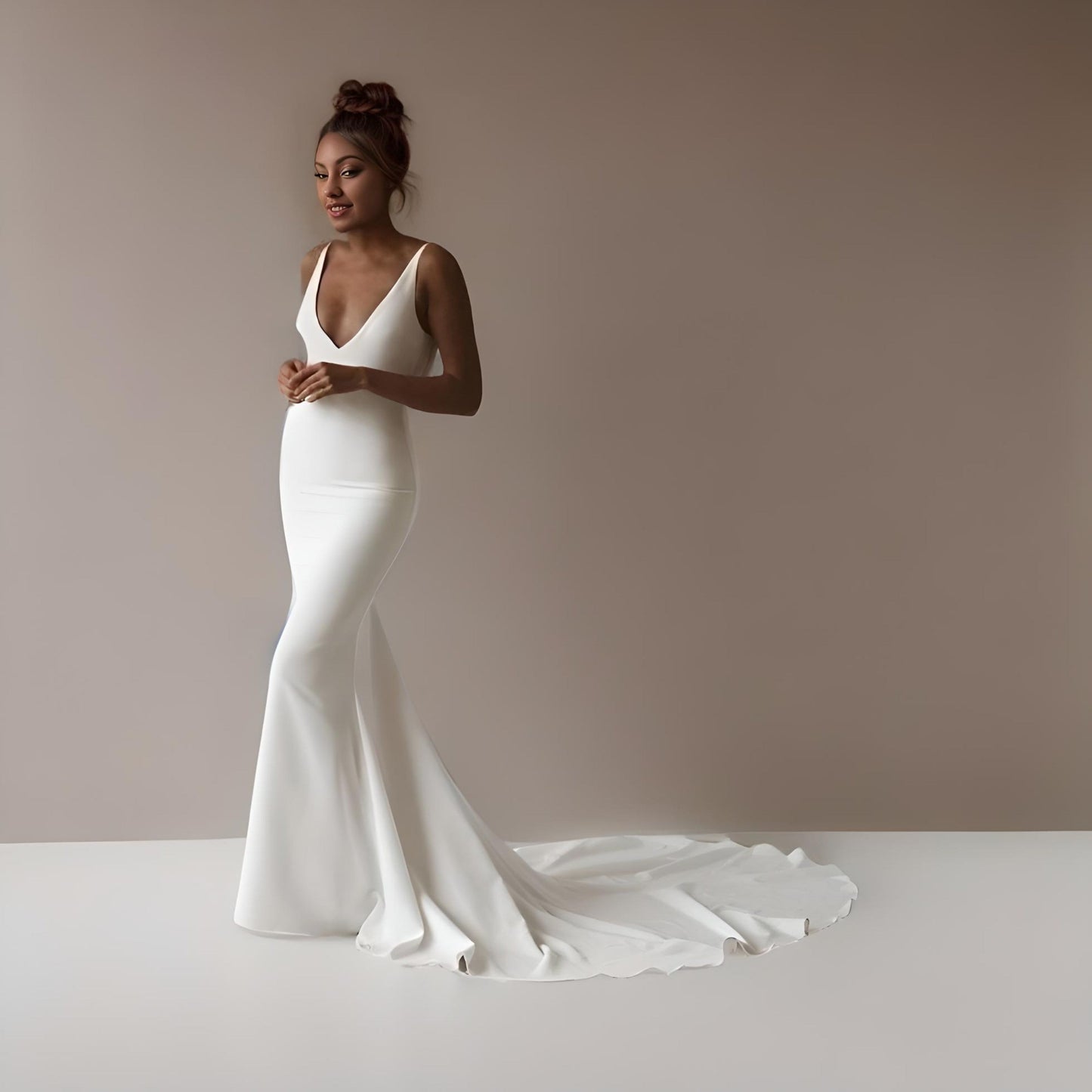 Model in a minimalist mermaid gown with a plunging back, backless design, and delicate back buttons.