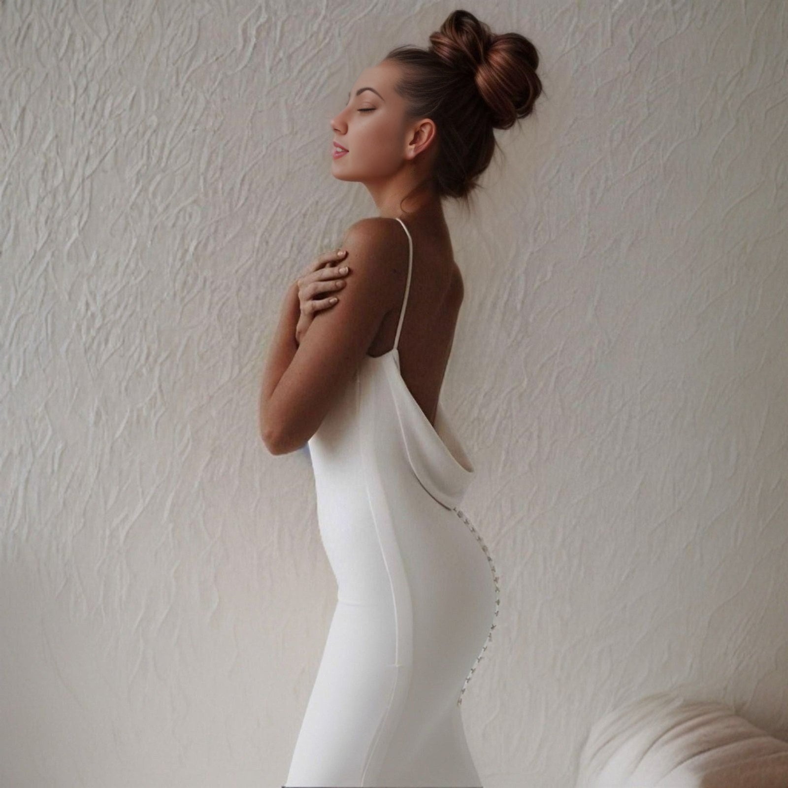 Woman from side wearing a simple mermaid wedding gown with a backless design and plunging fabric on lower back with back buttons.