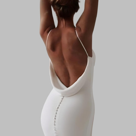 Model wearing a sleek and simple backless mermaid wedding dress with a plunging back.