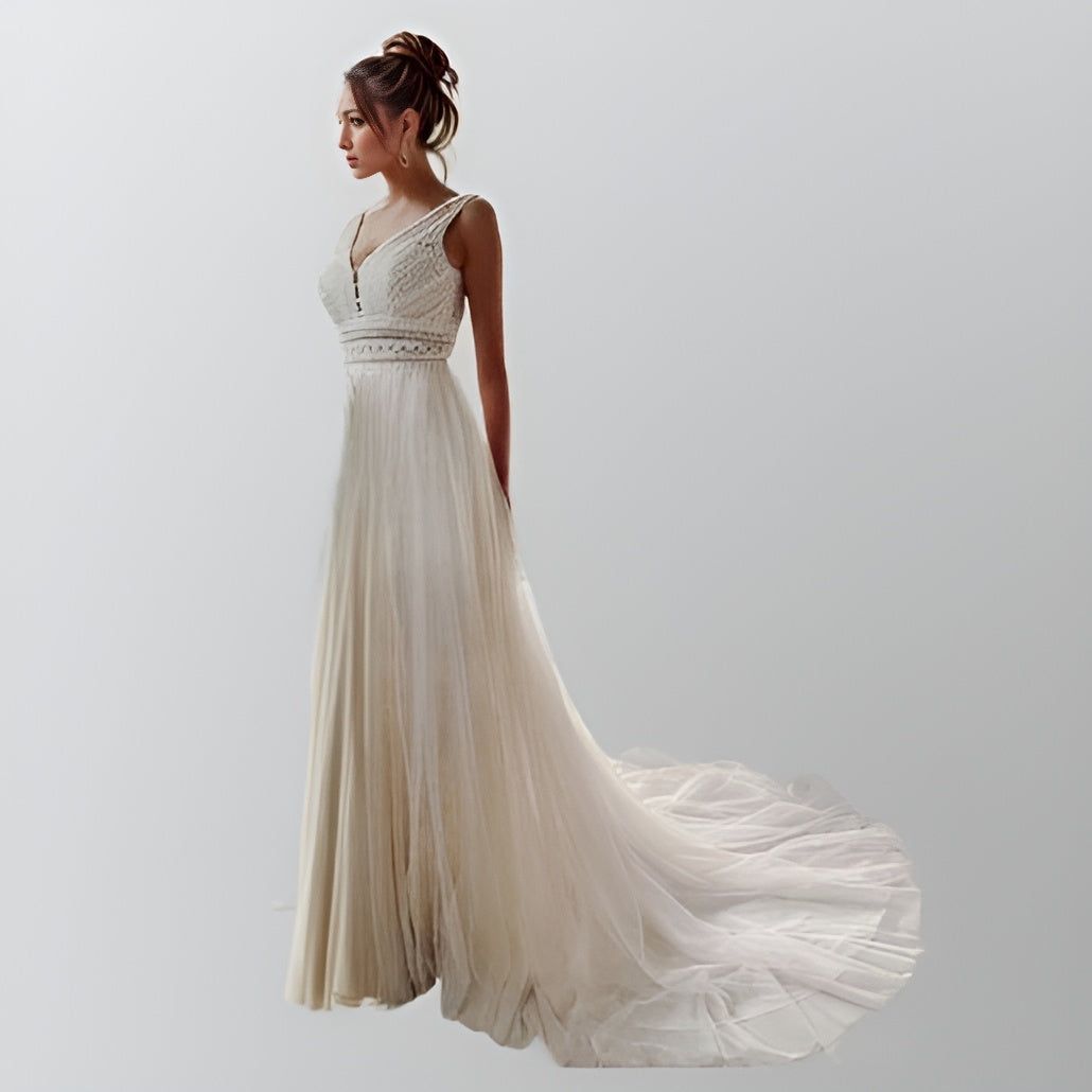 Model showcasing a bohemian-inspired wedding gown with a V-neckline, straight lace waist, and a flowing tulle A-line skirt with a sweep train.