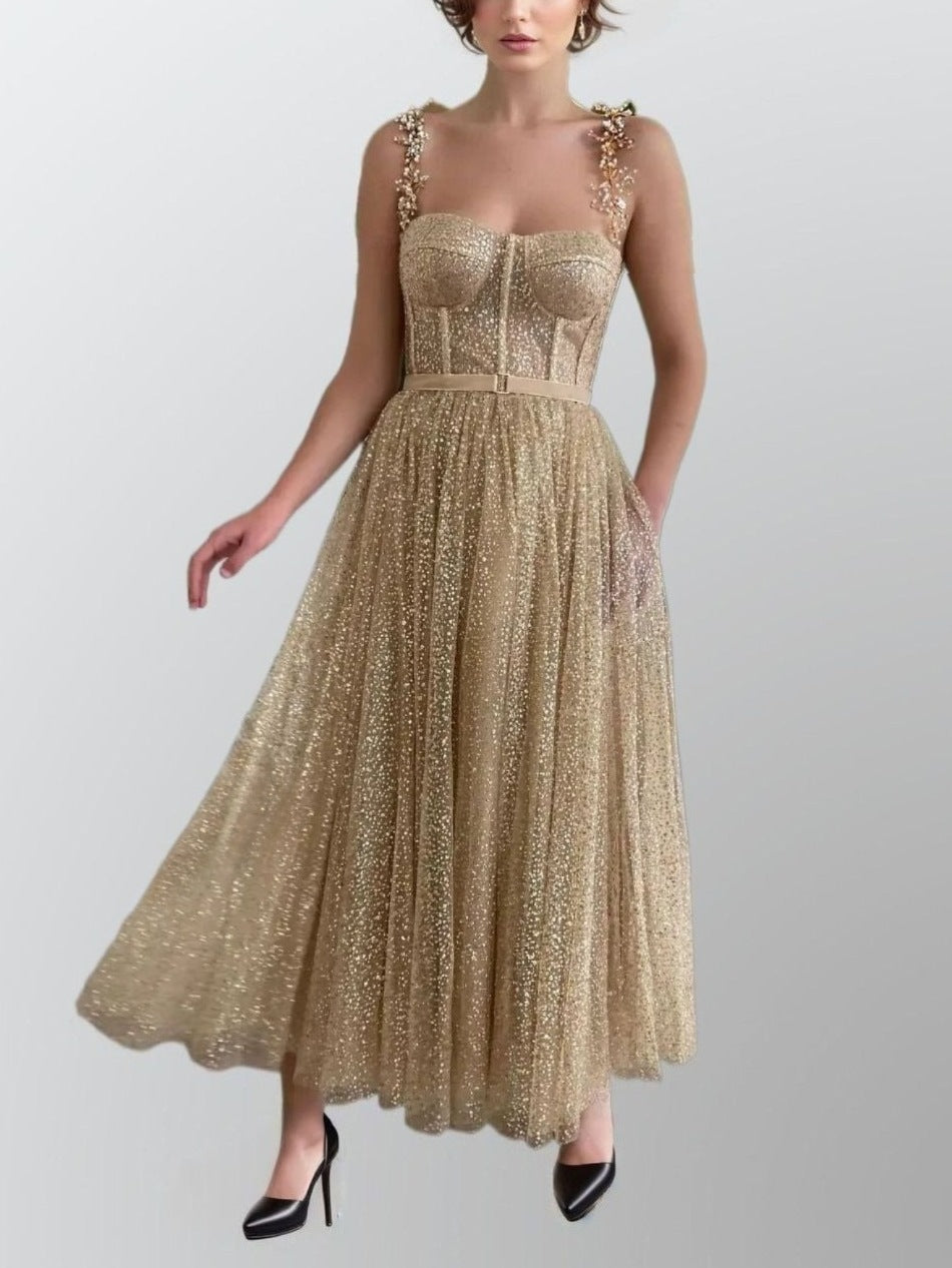 Model showcasing a gold glitter A-line gown with beaded spaghetti straps and tea-length skirt, complete with comfortable underskirt and pockets.