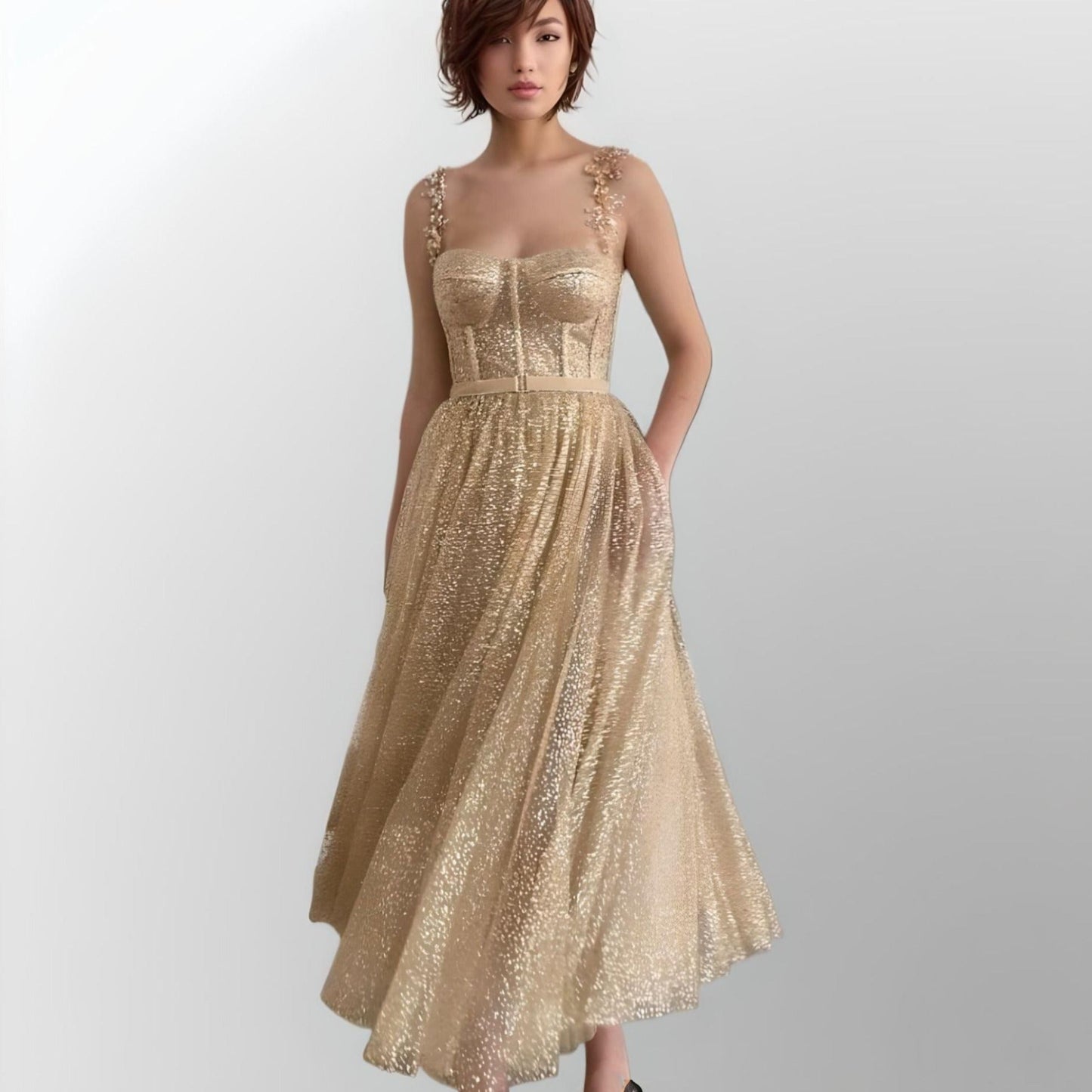 Model showcasing a gold glitter A-line prom dress with beaded spaghetti straps, a fitted bodice, and tea-length skirt, ideal for formal events.