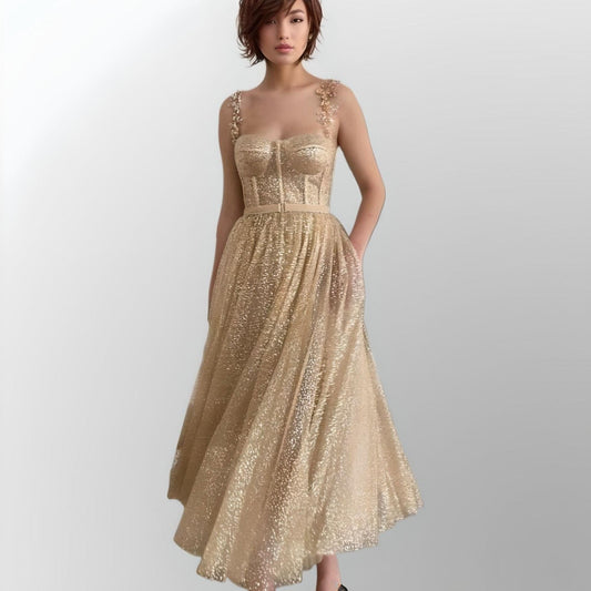 Model showcasing a gold glitter A-line prom dress with beaded spaghetti straps, a fitted bodice, and tea-length skirt, ideal for formal events.
