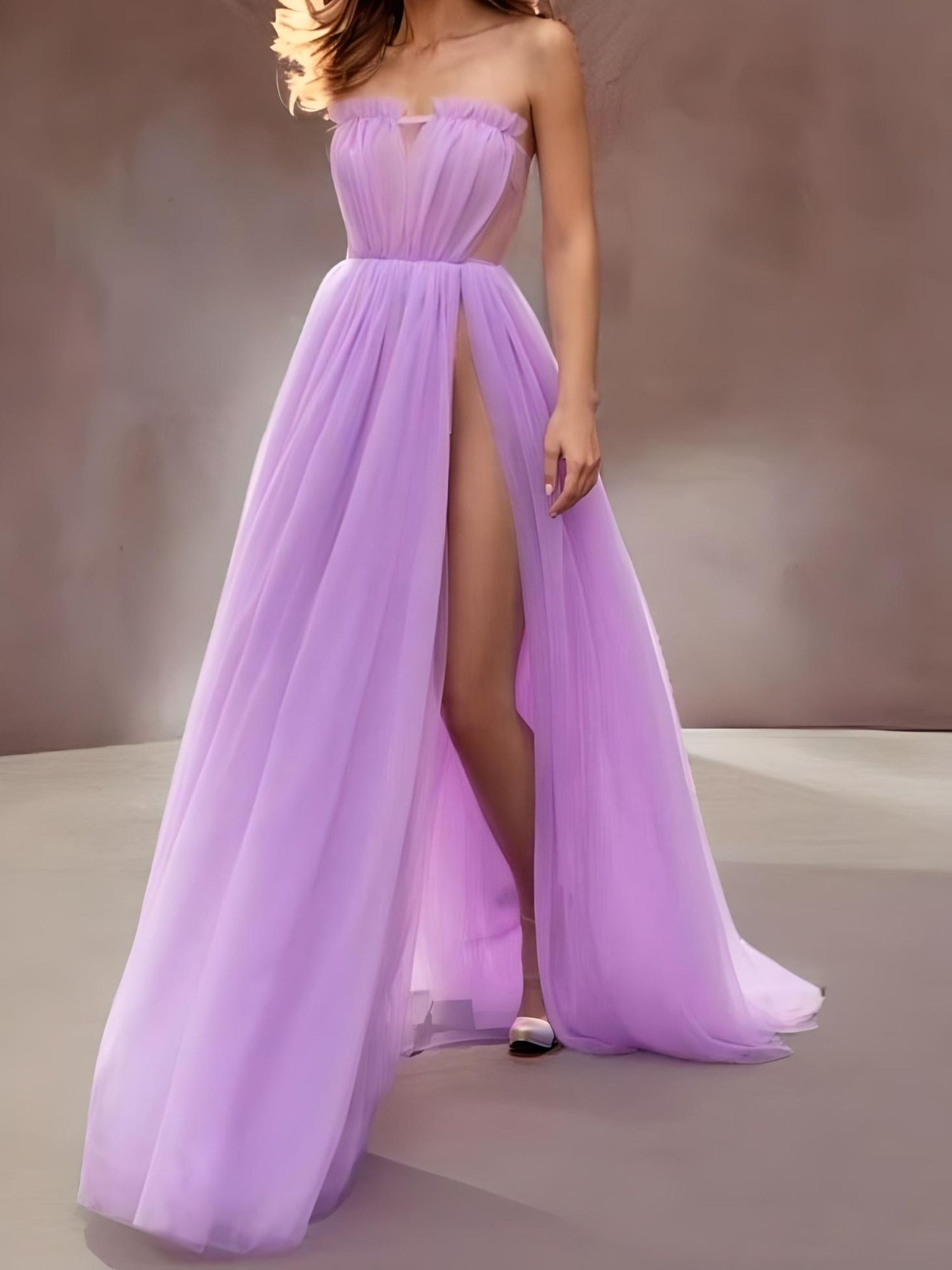 Model in a lavender gown featuring a strapless design, very high slit, and pleated detailing, perfect for prom or evening occasions.