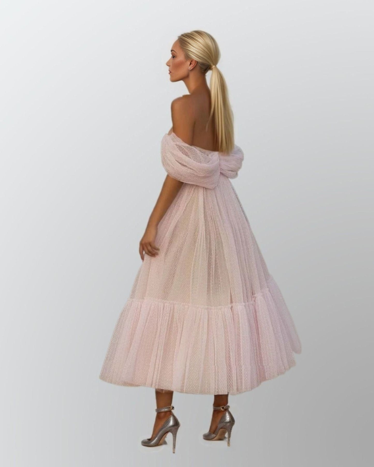 Woman from back in elegant tea-length formal gown featuring off-shoulder gathered sleeves, a pleated bodice, and a tiered tulle skirt, ideal for a chic party look.