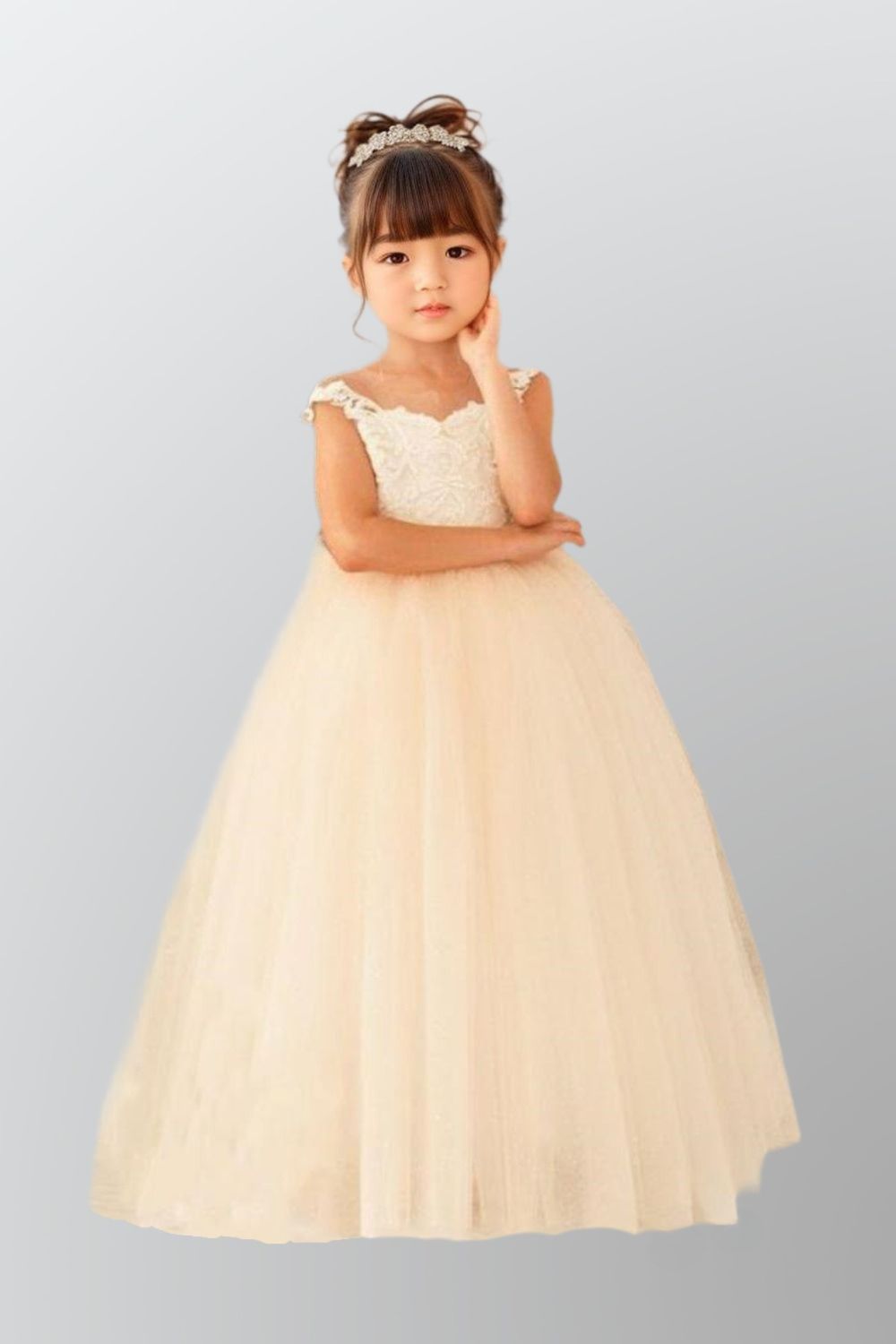 Girl wearing a flower girl gown with an off-shoulder design, lace top and tulle fabric, perfect for first communions or formal parties.
