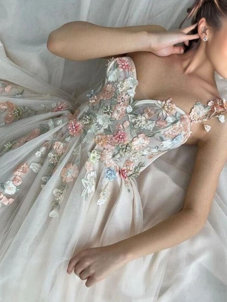 Woman lying in LIBBY gown, showcasing elegant 3D flower details.