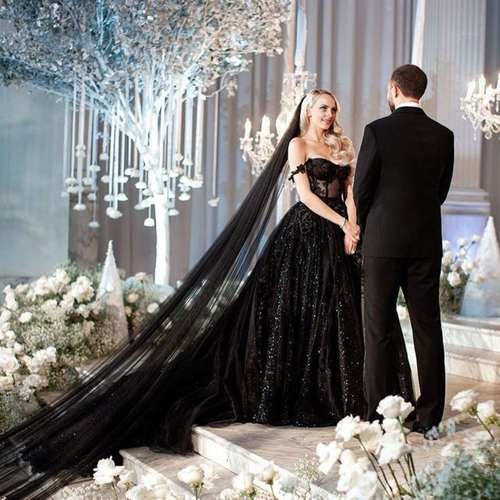 Groom standing in front of altar with bride in fully sequined black gown wearing long black veil.