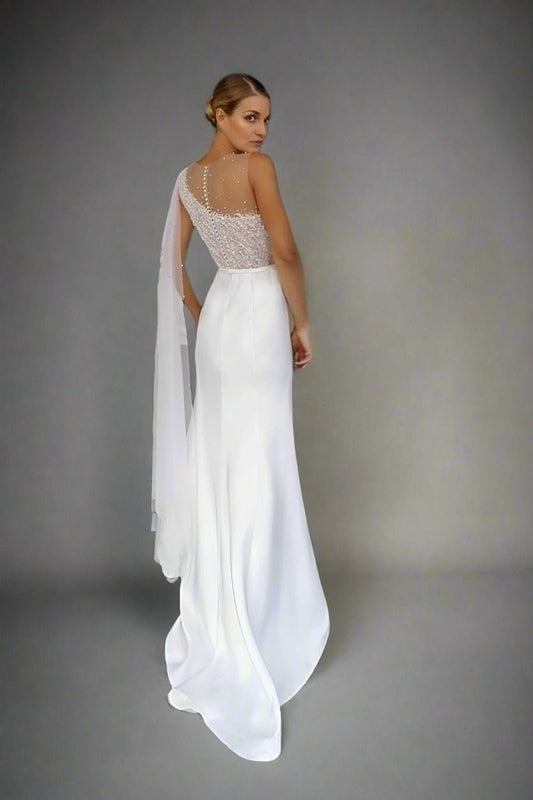 Woman in asymmetrical one shoulder beaded top wedding dress and one shoulder veil.