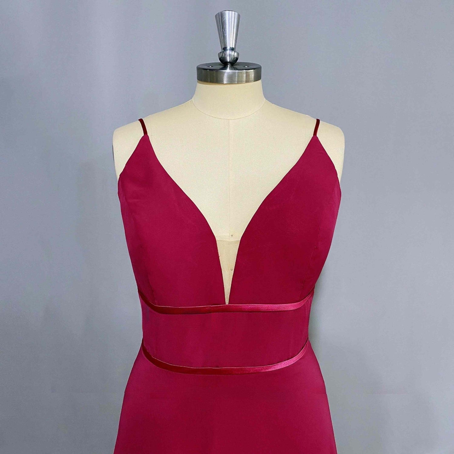 Store mannequin in elegant formal dress featuring a V-neckline, spaghetti straps, and two waist-accentuating straps, ideal for a stylish bridesmaid or prom look.