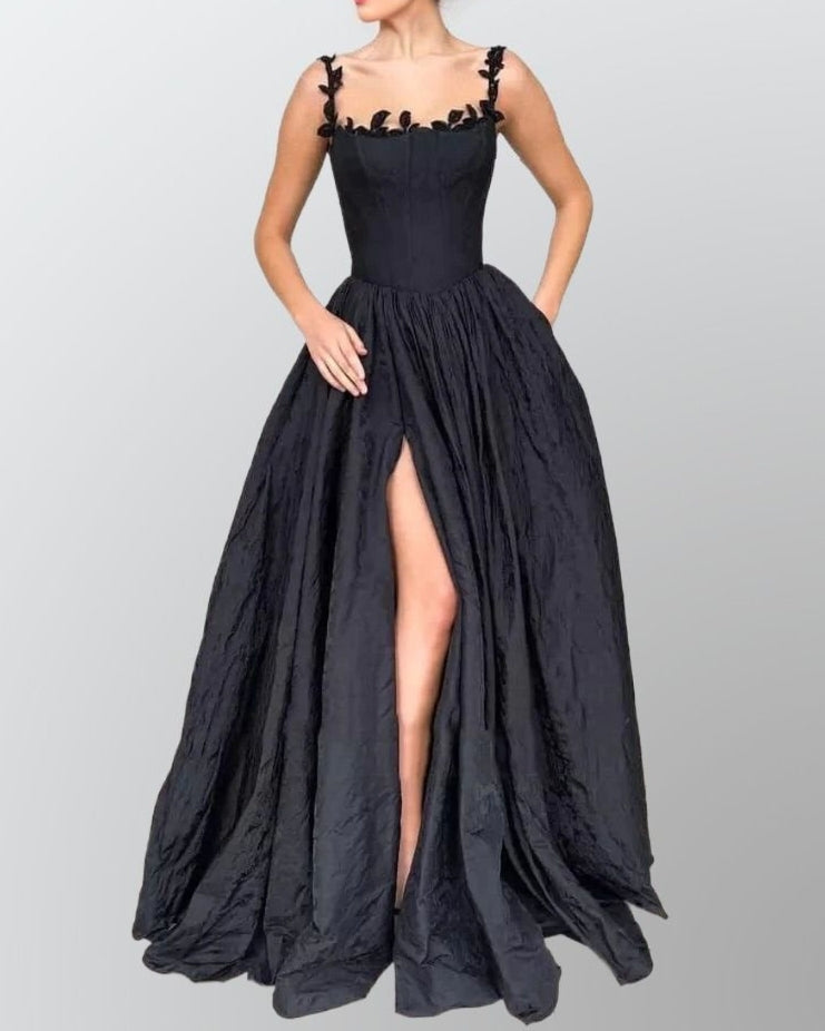 Woman wearing the LACIE dress, showcasing the high side split and leaf lace details in black.