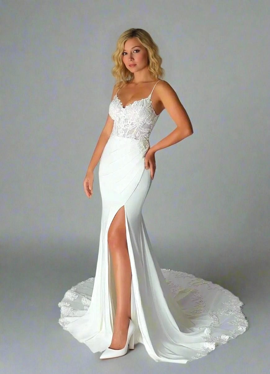 Bride posing in romantic floor-length wedding dress with lace bodice, high slit and lace train