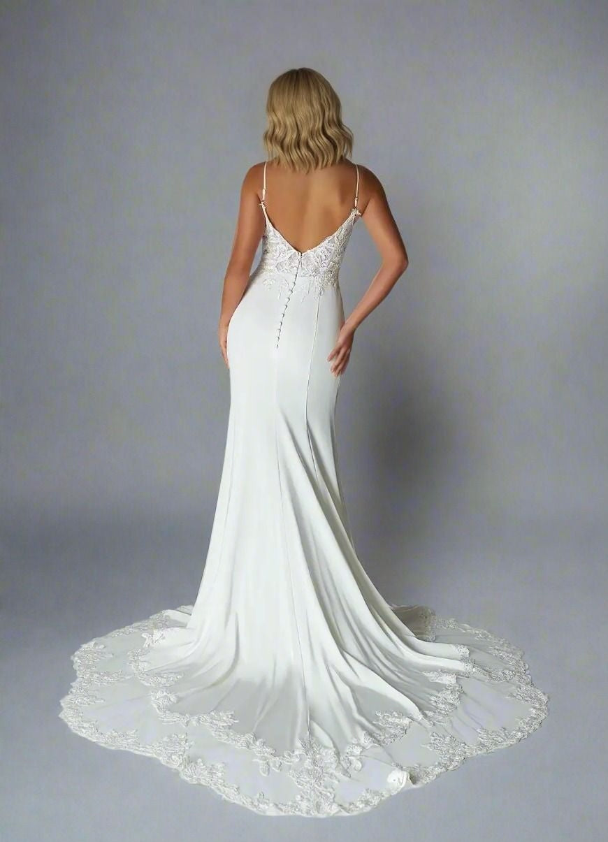 Bride from back in soft lace bodice applique bridal gown with spaghetti straps, button back details and lace train