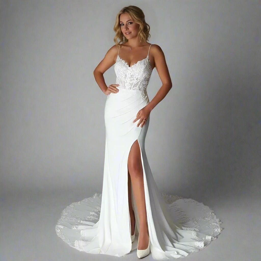 Blond woman in floor-length wedding dress, showing high slit, lace bodice and and beautiful lace train