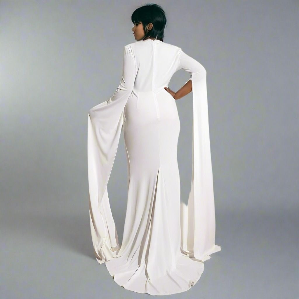 Woman with short black hair showing ack of Sonya Dress showing the sweep train and sweep sleeves in elegant silhouette.
