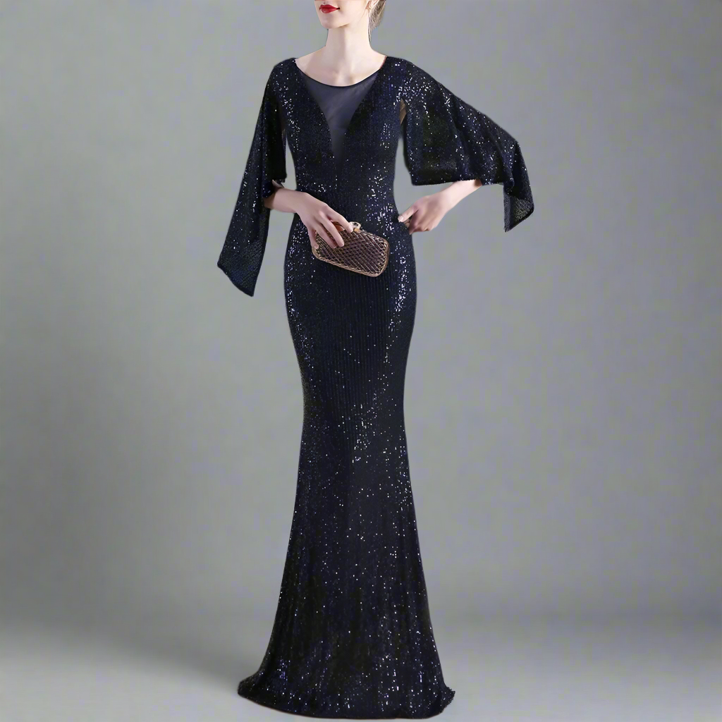 Woman in a sparkly navy evening gown holding a clutch in studio setting.