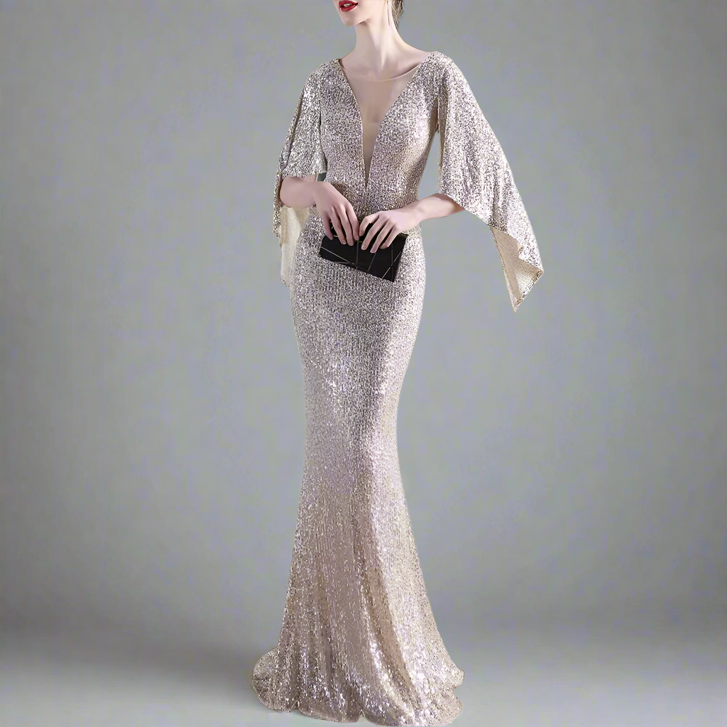 Woman in a sparkly evening gown holding a black clutch in an indoor setting.