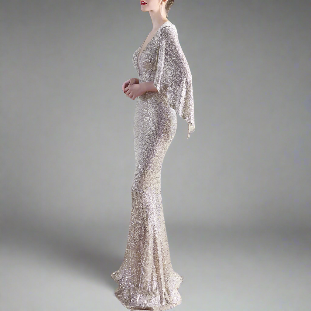 Woman wearing a sparkly silver evening gown with cape bat sleeves