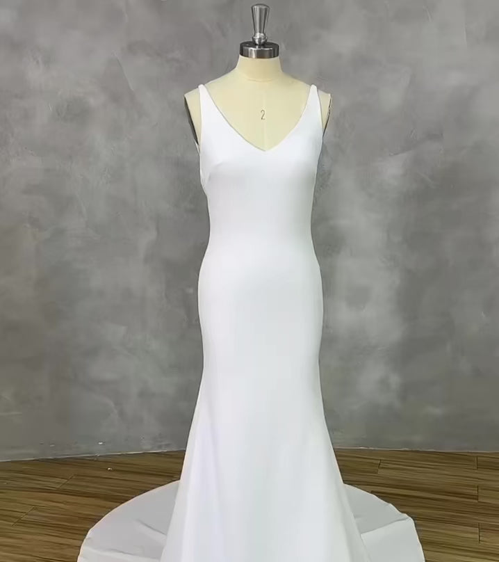 Video showcasing a backless mermaid bridal gown with a plunging back and button detailing on a mannequin.