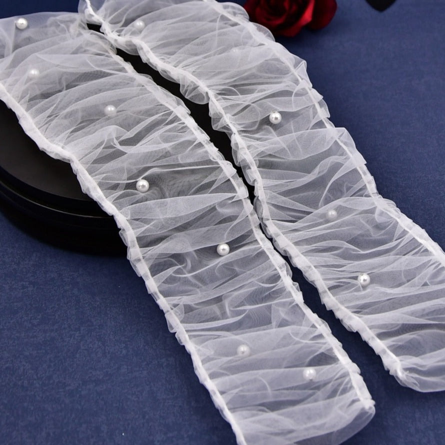 Close-up of pearl-adorned bridal sleeves with ruched tulle.