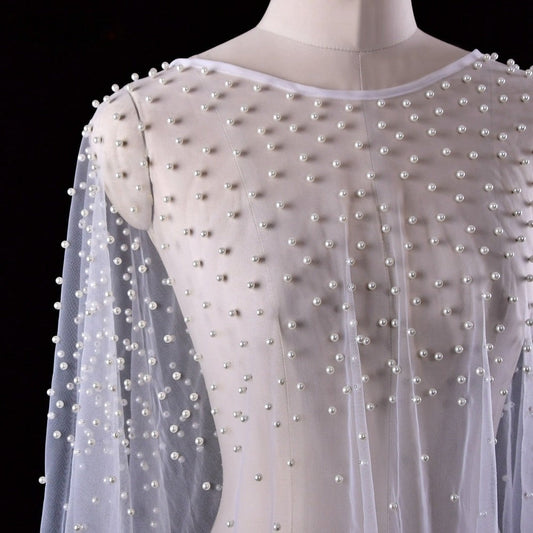 Close-up of delicate pearl beading on sheer bridal bolero cape.