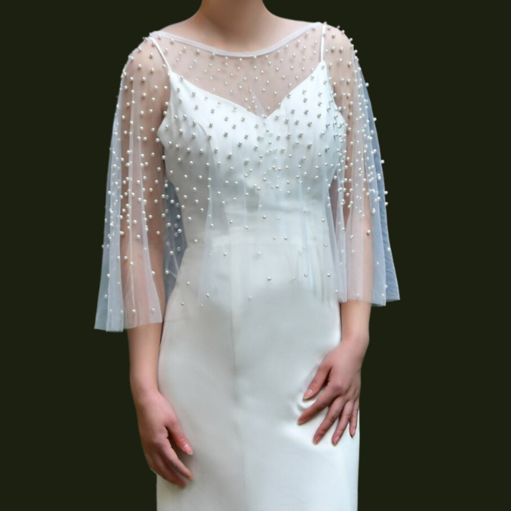 Bride showcasing transparent wedding cape with pearl details.