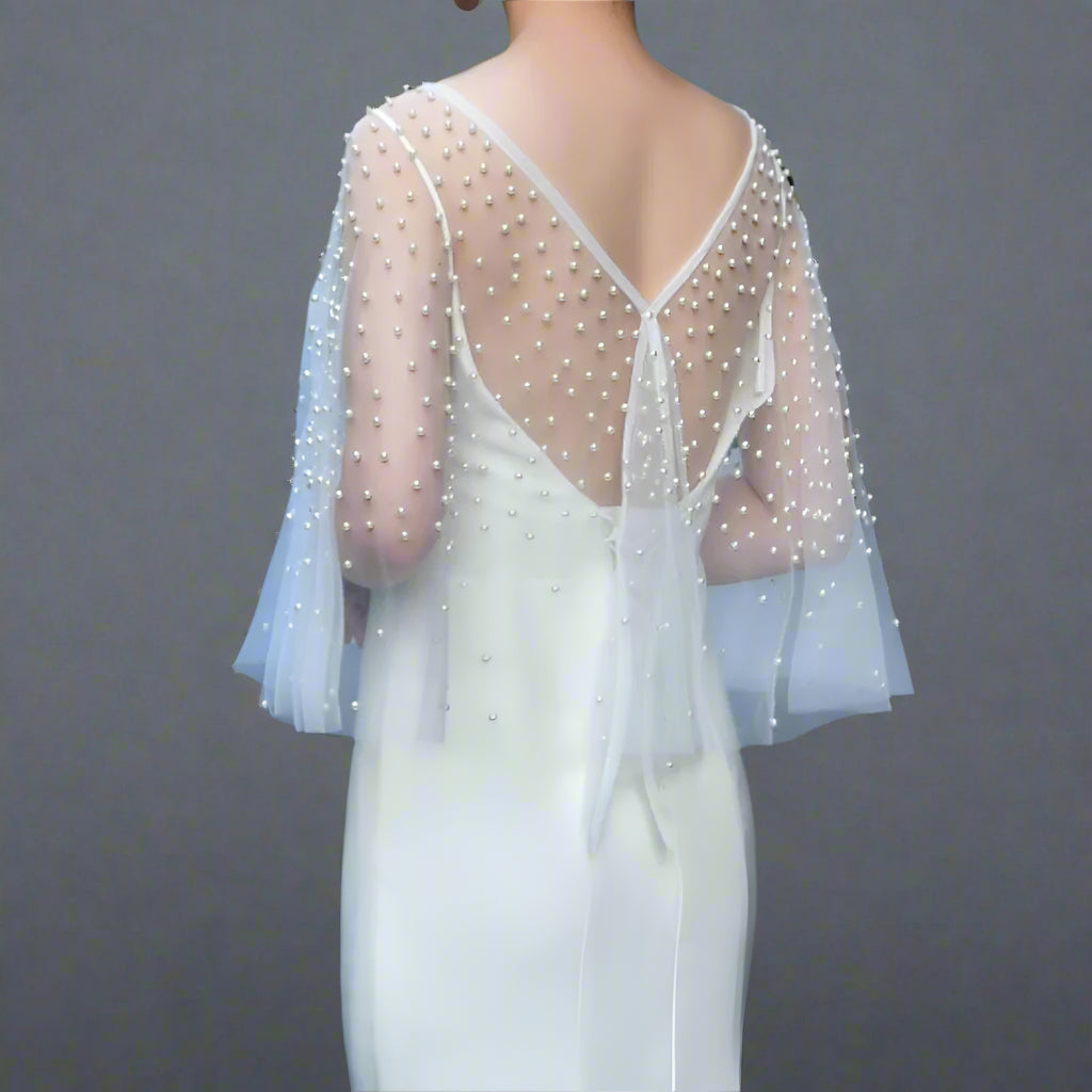 Bride showcasing transparent wedding cape with pearl details from back.
