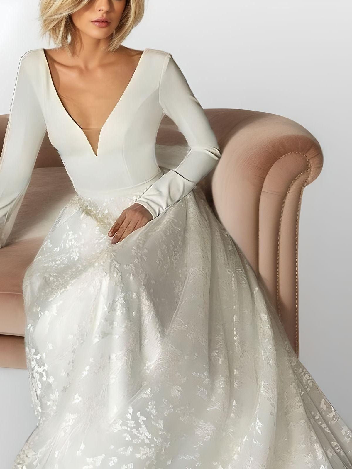 Bride sitting and showing the elegant long sleeves and lace appliques of SARAH wedding dress.