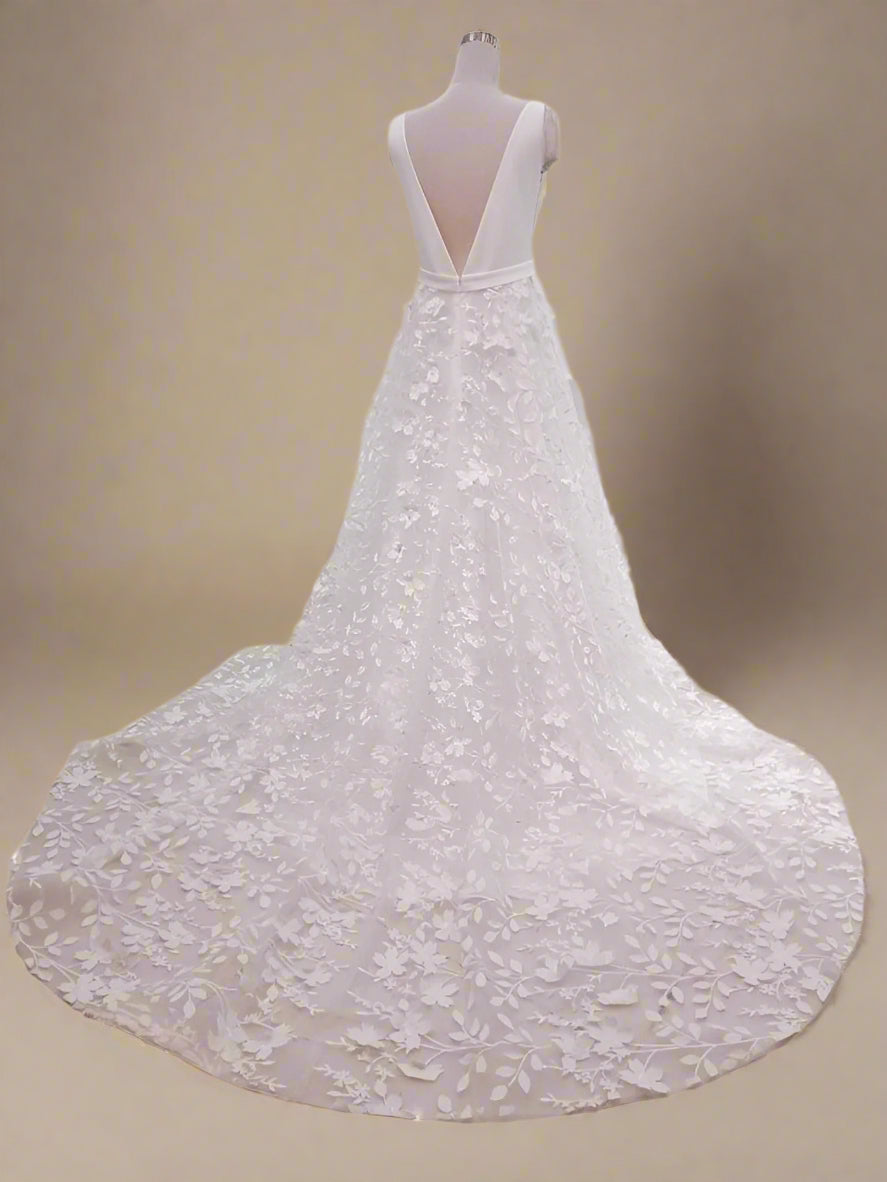 Back view of boehmian SARAI wedding dress with deep V-back and sweep train on a figurine.