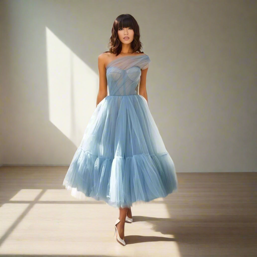 Brunette wearing dusty blue one-shoulder SKYLAR Formal Dress with corset design and pleated tulle skirt.