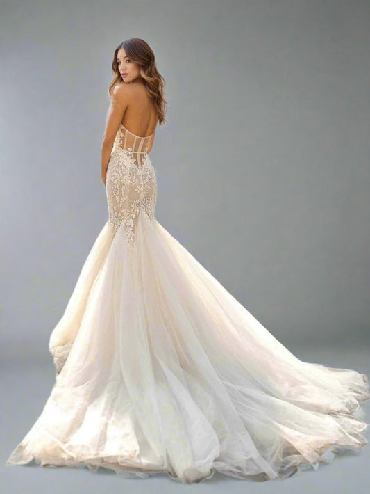 Bride posing in a lace and tulle mermaid wedding dress with a full bottom showing backless wedding dress with lace details and sheer bodice.