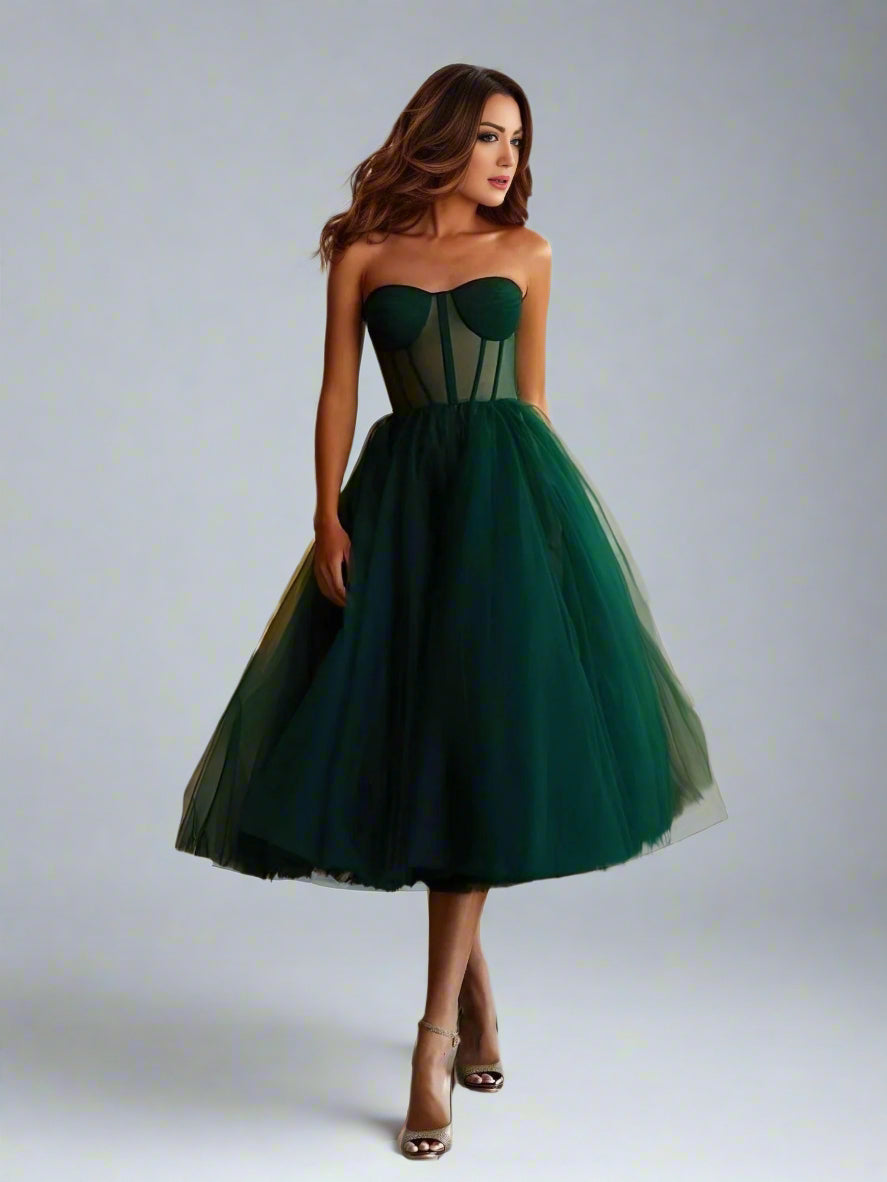 Brunette in elegant emerald green Vanessa tea-length party dress perfect for evening events.